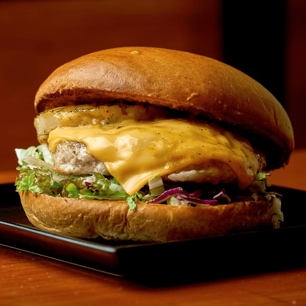 A Thirsty Lizard Bar & Grill burger with melted cheese, pineapple, lettuce, and red cabbage.